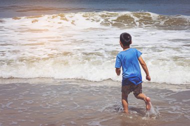 Küçük çocuk kumsalda oynuyor.