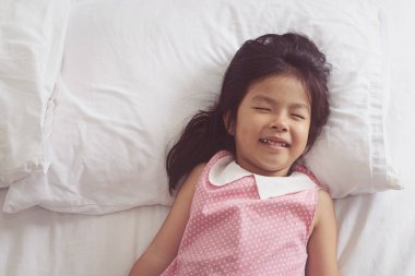 Asyalı küçük kız yatakta uyuyor.