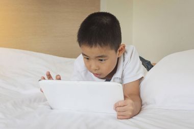 Yatakta tablet bilgisayar kullanarak Asya küçük çocuk