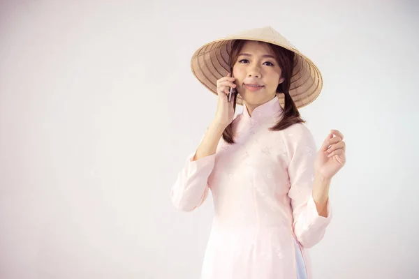 Hermosa mujer en vestido rosa y sombrero vietnam celebración de teléfono inteligente — Foto de Stock