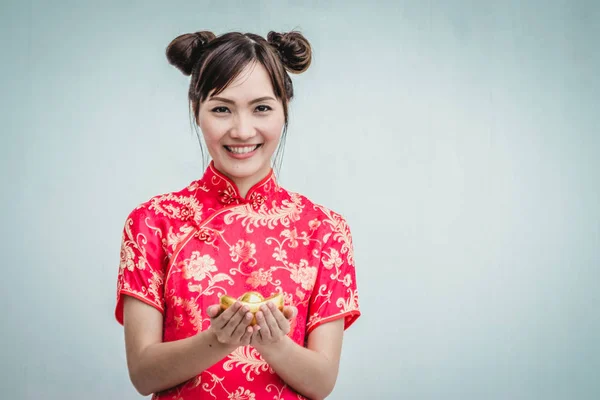 Mujer asiática con cheongsam sosteniendo oro. Año nuevo chino . — Foto de Stock