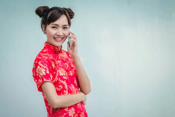 Mujer asiática con cheongsam celebración de teléfono inteligente . — Foto de Stock