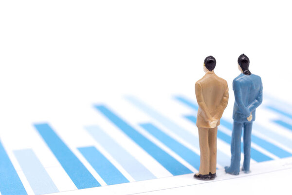 Miniature figures businessmen standing on a graph chart financia