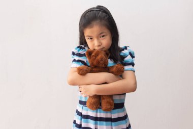 Asyalı kız oyuncak ayıya sarılıyor.