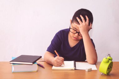 Sıkıcı ve yorgun Asyalı öğrenci ev ödevi yapıyor. 