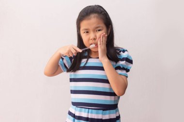 Asyalı kızın diş fırçası tutarken dişi ağrıyor. 