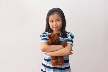 Asyalı kız oyuncak ayıya sarılıyor.
