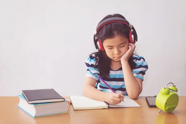 Asiática niña escribiendo un libro y auriculares escuchando mu — Foto de Stock