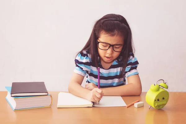 Asijské holčička psaní knihu na stůl — Stock fotografie