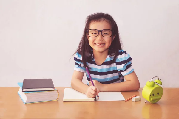 Asiatisk liten flicka skriver en bok på bordet — Stockfoto