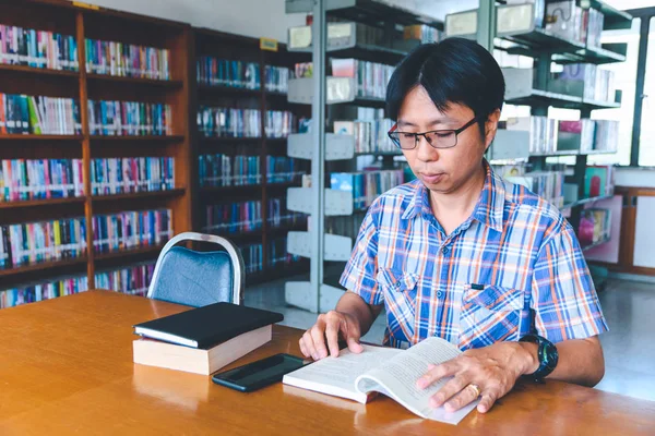 Smiling asian man student working in a library