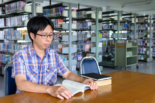 Smiling asian man student working in a library