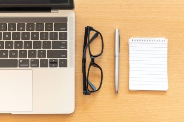 Ofis ahşap masasında dizüstü bilgisayarı ve not defteri olan en iyi görüntü masası.