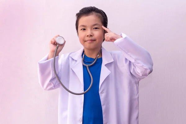 Asian girl playing doctor with stethoscope in hands.