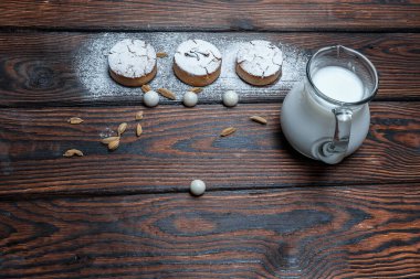 Taze süt ya da yoğurt bardağa doldurulur. Mavi bir standın üzerinde koyu metal bir arka planda bir cam bulunur. Yakınlarda çikolatalı yulaflı kurabiyeler var. Yakın çekim, mesaj için yer. Sığ alan derinliği.
