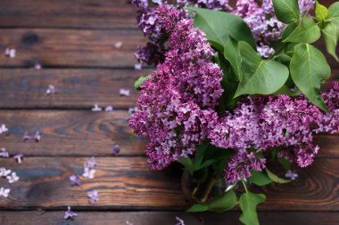 Koyu, ahşap bir arka planda mor leylak dalları. Masada düşmüş leylak çiçekleri. Metin için boşluk. Seçici odaklanma. Sevgililer Günü ve Anneler Günü geçmişi