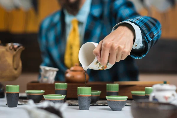 Un homme verse du thé chinois dans des tasses pour une cérémonie du thé — Photo