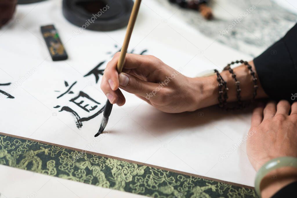 man writes with a brush hieroglyphs on paper