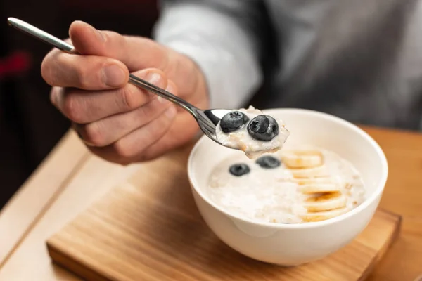 Teller mit Reisbrei auf dem Tisch und einem Löffel in der Hand. — Stockfoto