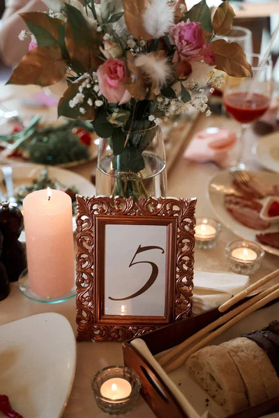 Table with food, flowers, candles and table number. Celebratory banquet.