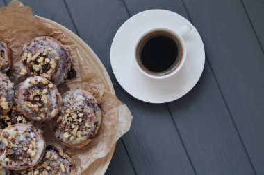 Güzel taze tarçın ruloları ahşap grunge doku masasına yakın çekim. Ev yapımı kekler, Cinnabon. Beyaz çay tabağında bir fincan çay, tarçın çubukları. Lezzetli Kahvaltı Büfesi