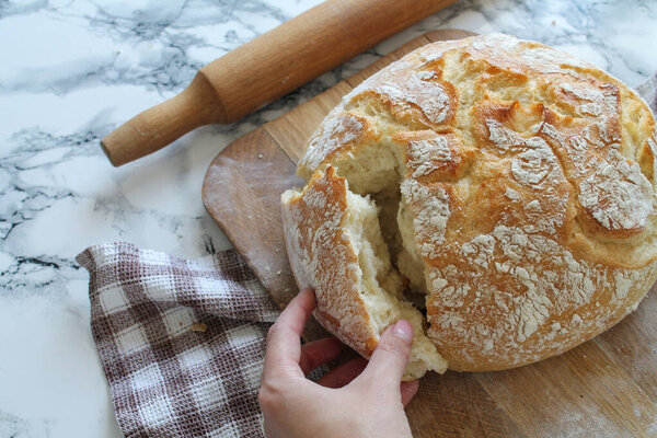 Рука молодой женщины разбивает хлеб крупным планом
