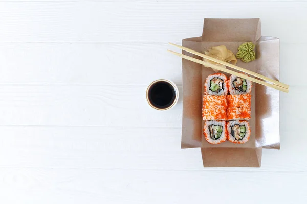 Restaurant healthy food delivery in take away eco biodegradable boxes for daily nutrition on white background. Japanese sushi close-up with copy space