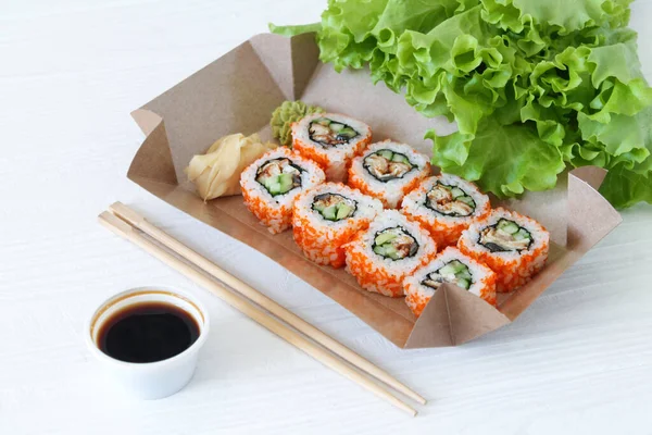 Japanese sushi to go. Biodegradable take away craft box with sushi maki rolls california. Asian food with smoked eel, avocado, cucumber and red caviar. Healthy snack delivery.