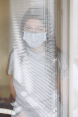 Pencerenin yanındaki bilgisayar başındaki kız, Coronavirus, covid-19.