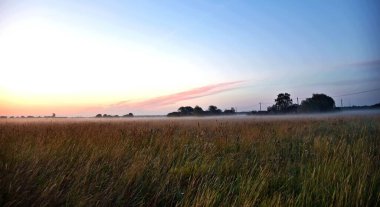Baltık Denizi 'nin yakınındaki bir tarlada sersemletici bir gün doğumu. Estonya.
