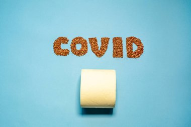 Mavi arkaplanda karabuğday yazıtları var. Tam ortasında İngiliz harfleri ve yan yazının altında tuvalet kağıdı var.