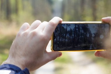 Ormanda akıllı telefondan fotoğraf çeken adam, ellerinde akıllı telefon, dışarıda cep telefonuyla fotoğraf çeken erkek.