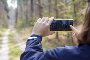 Ormanda akıllı telefondan fotoğraf çeken adam, ellerinde akıllı telefon, dışarıda cep telefonuyla fotoğraf çeken erkek.