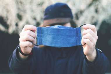 El yapımı pamuk yüz maskesi, arka planda insan, virüslerden korunma.