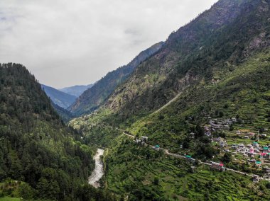 Bulutlu havada güzel dağ vadisi manzarası. Yollar, nehir ve tarım manzarası.