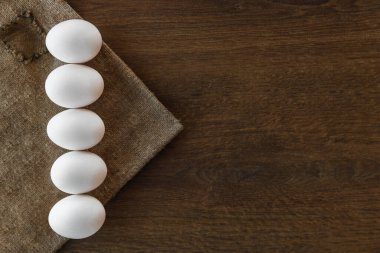 Kahverengi ahşap arka planda ve çuval bezinde beyaz Paskalya yumurtası çizgisi. 