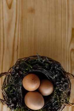 Paskalya doğal yumurtaları sarı doğal ahşap arka planda sepette. Dikey