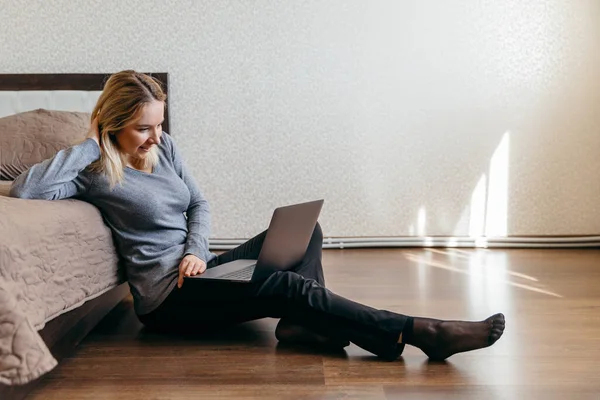 Woman sitting on the floor in bedroom and having Zoom video conference call via computer withfriend. Zoom Call Meeting. Home as hub during Coronavirus pandemic