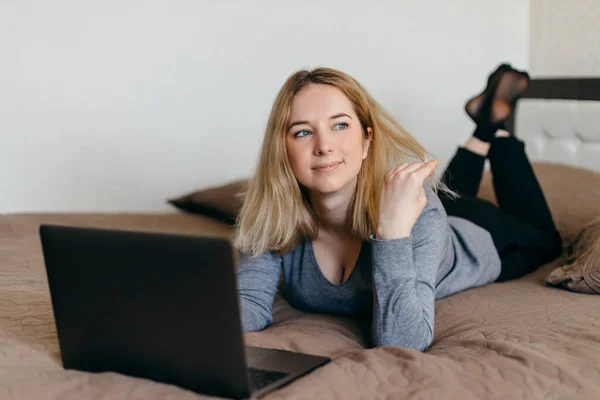 Woman lying on the bed in living room and having Zoom video conference call via computer withrelatives. Zoom Call Meeting. Home office. Stay at home and work from home concept during Coronavirus