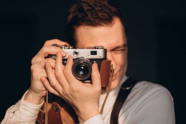 Eski bir kamerayla fotoğraf çeken genç bir adamın portresi..