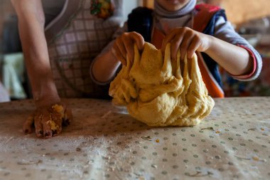 Çocuk kız, anneye ekmek hazırlamada yardım eder. Eller hamuru yoğurur. Anneler Günü konsepti