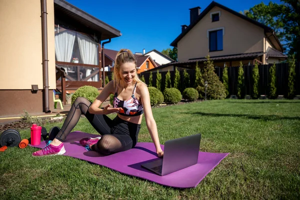 Pretty sportive fitness coach woman using laptop during online video training.