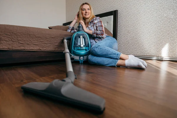 Retired woman  sitting on the floor at bedroom after hoovering  and cleaning.