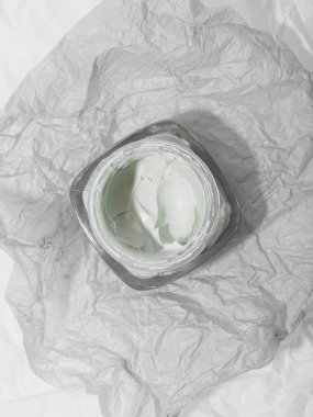  Buruşuk gri arka planda bir kavanoz krema.