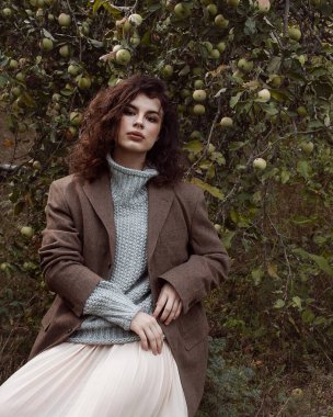 Kazaklı kıvırcık kız elma bahçesinde yürüyor.