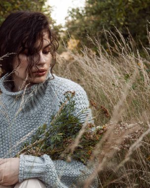 Kazaklı kıvırcık kız elma bahçesinde yürüyor.