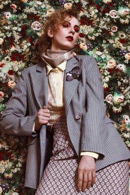 Çiçek desenli arka planda basılı elbiseli bir kız.