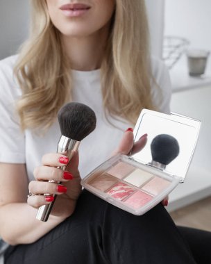 Kız elinde fırça ve göz farı tutuyor.