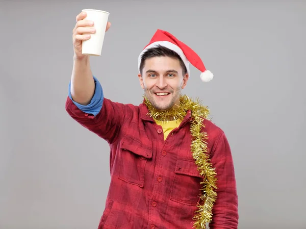 Divertido joven borracho con sombrero de Santa sosteniendo una taza de papel — Foto de Stock