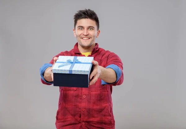 Улыбающийся счастливый молодой человек преподносит подарок — стоковое фото